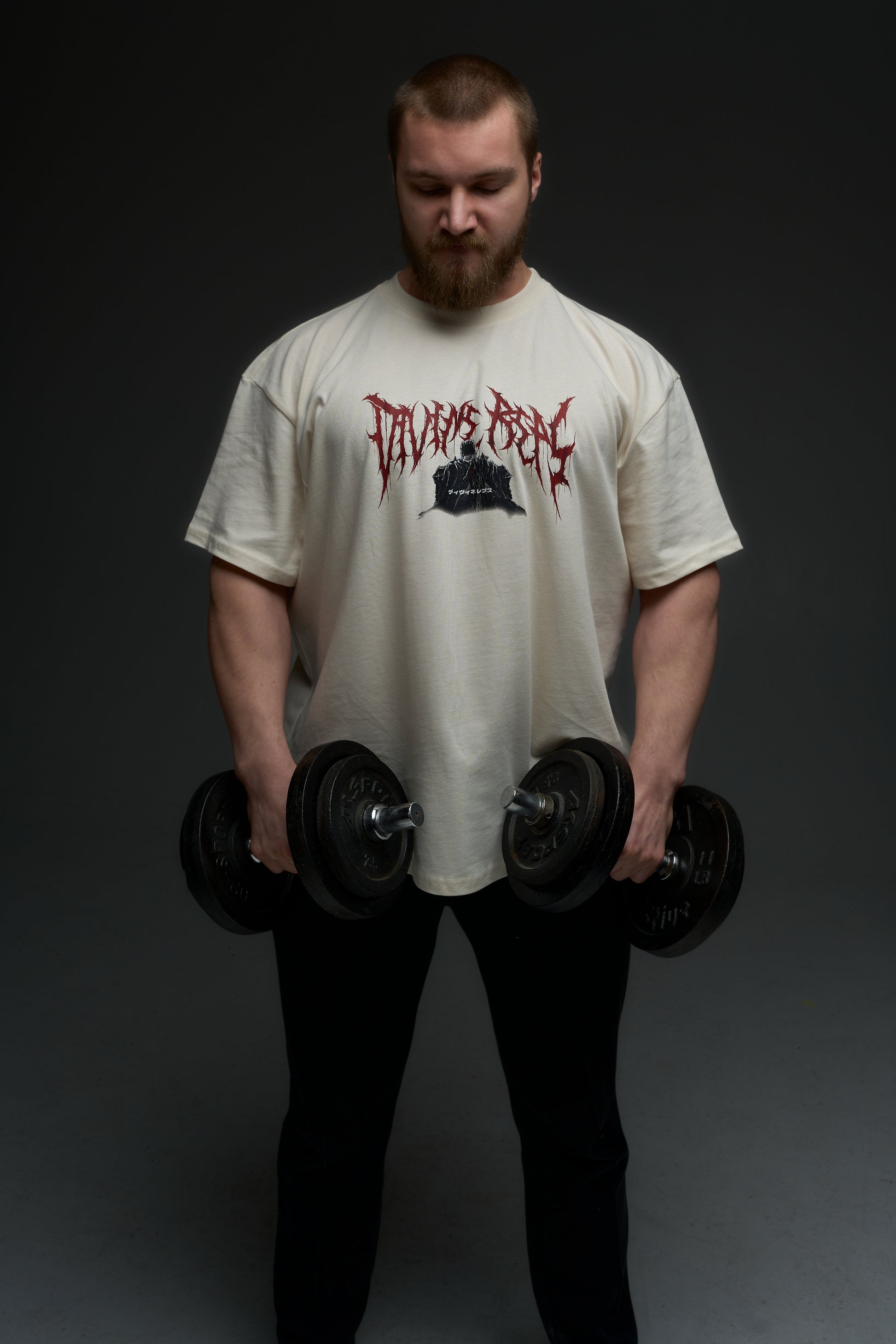 Model holding dumbbells in the natural raw Guts armor tee - front view with red Divine Reps chest logo